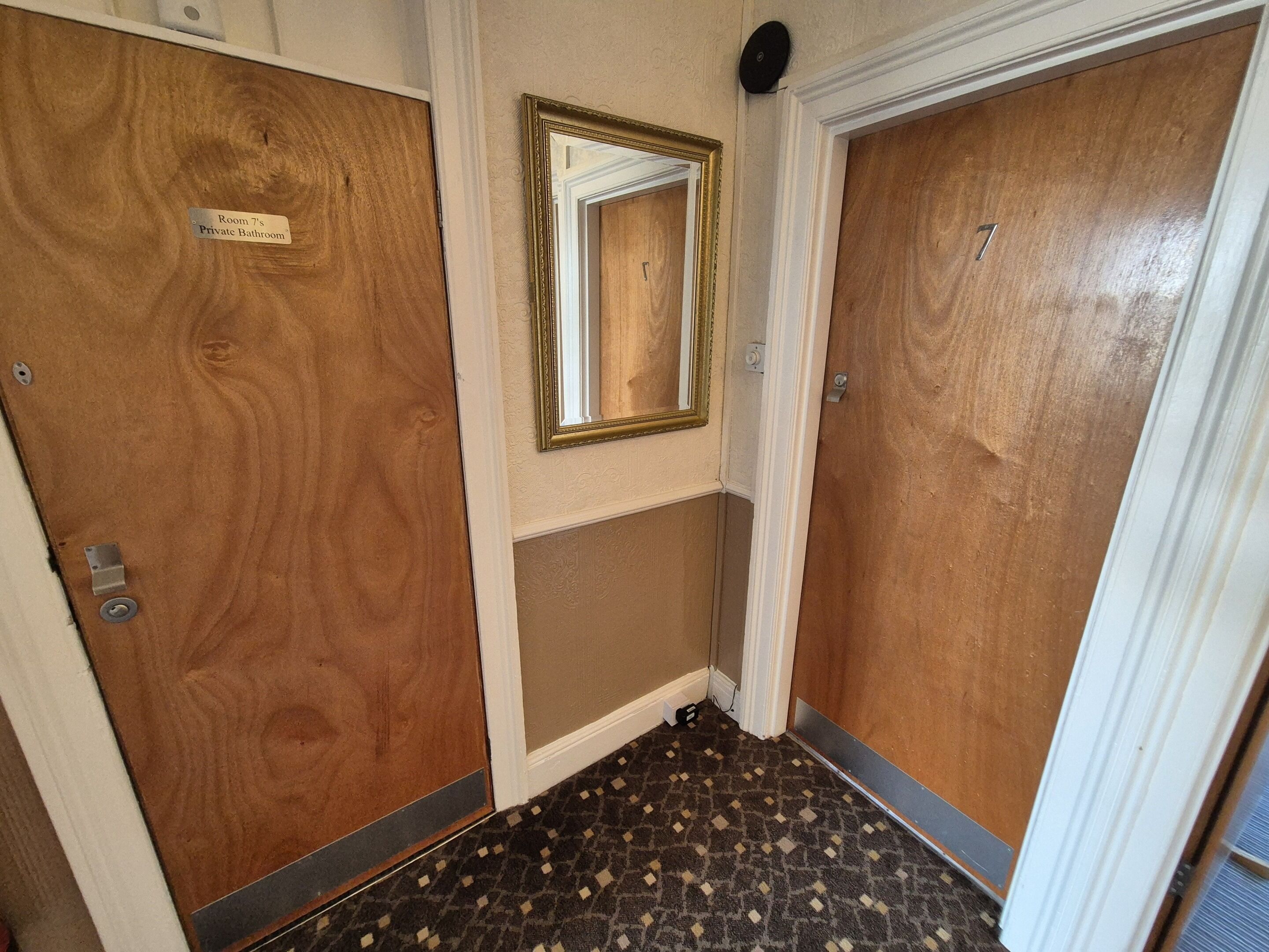 A hallway with two wooden doors, one labeled 'Room 7's Private Bathroom.'