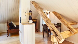 Un interior rústico con vigas de madera, un banco, una mesa y una araña.