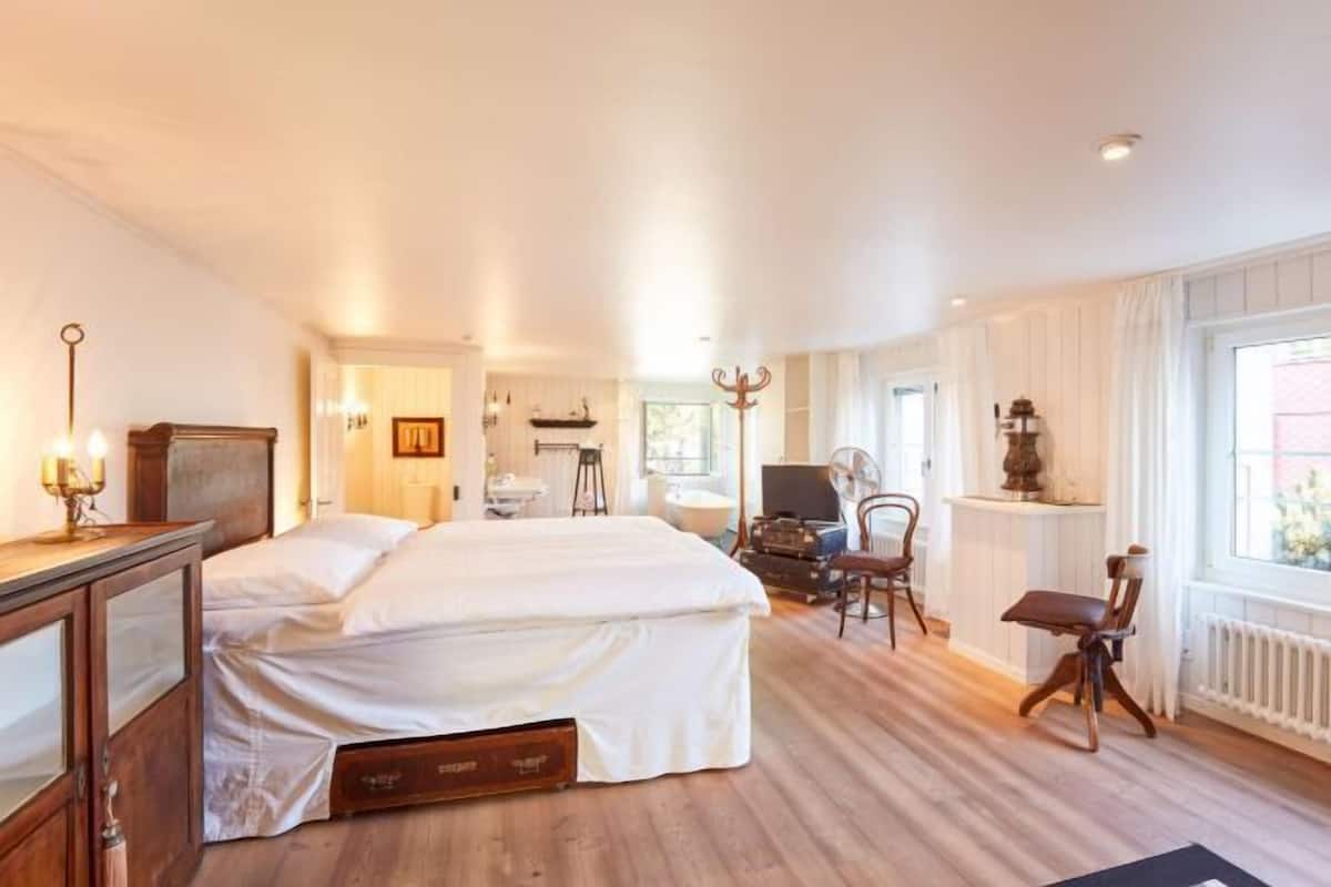 Ein Schlafzimmer mit einem Bett, einem Schreibtisch, einem Stuhl, einem Fernseher und einem Fenster.