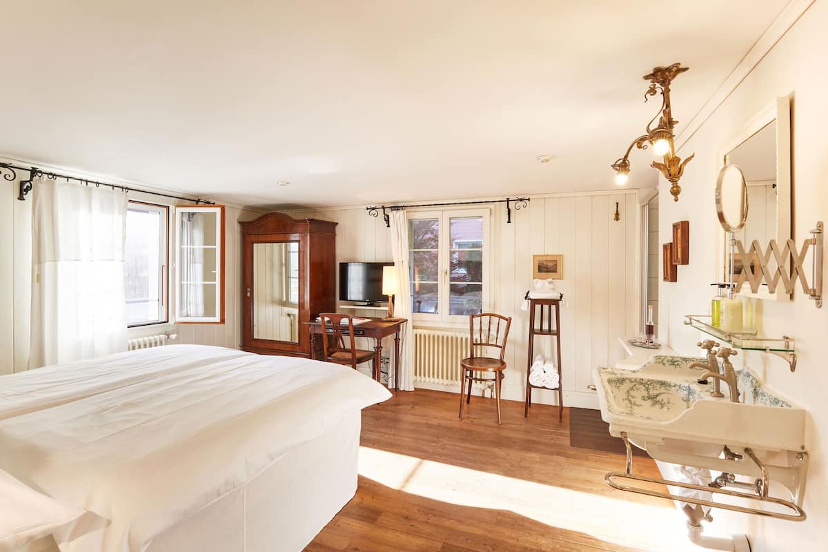 Ein Schlafzimmer mit einem großen Bett, einem Schreibtisch, einem Stuhl, einem Schminktisch mit Spiegel und einem Fernseher.