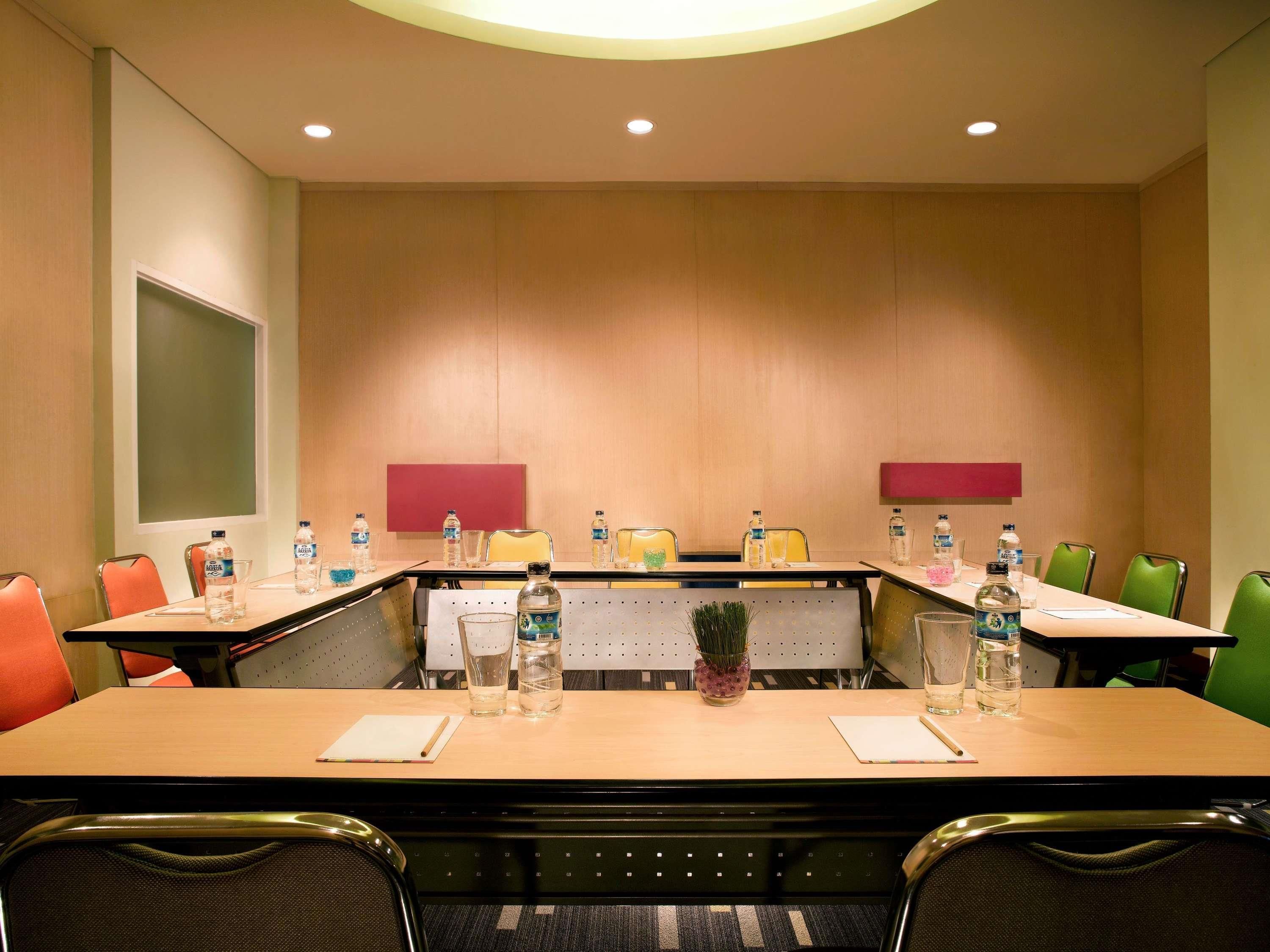 A conference room with a long table, chairs, water bottles, and a small plant.