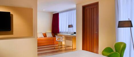 A hotel room with a bed, a desk, a chair, a TV, and a wardrobe.