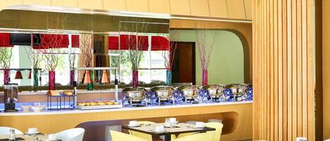 A restaurant with a counter displaying food, colorful chairs, and a wooden wall.