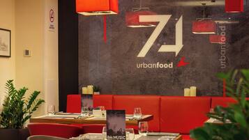 A restaurant interior with a modern design, featuring red seating, a large wall with the number 71, and a menu stand.