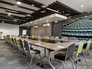 A conference room with a long table, chairs, and a projector screen.