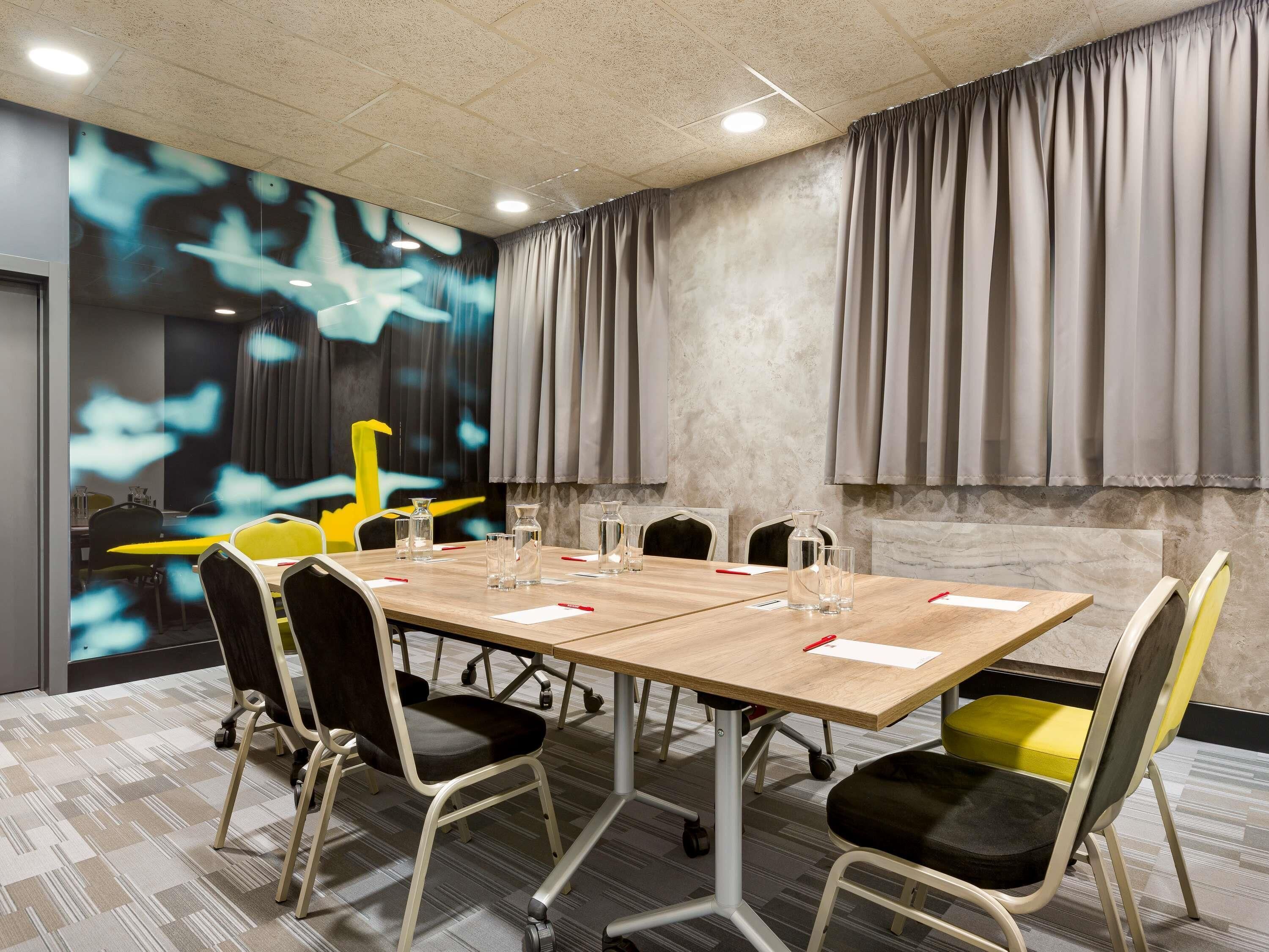 A conference room with a long table, chairs, and a projection screen.