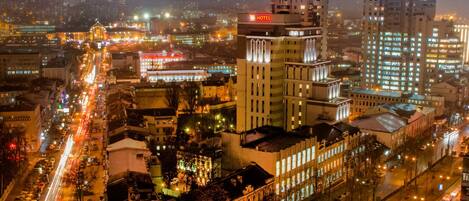 Un paisaje urbano nocturno con edificios iluminados, incluyendo un hotel con un letrero destacado.