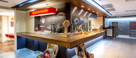Una zona de cocina con mostrador, taburetes y un letrero que dice 'ibis Kitchen'.