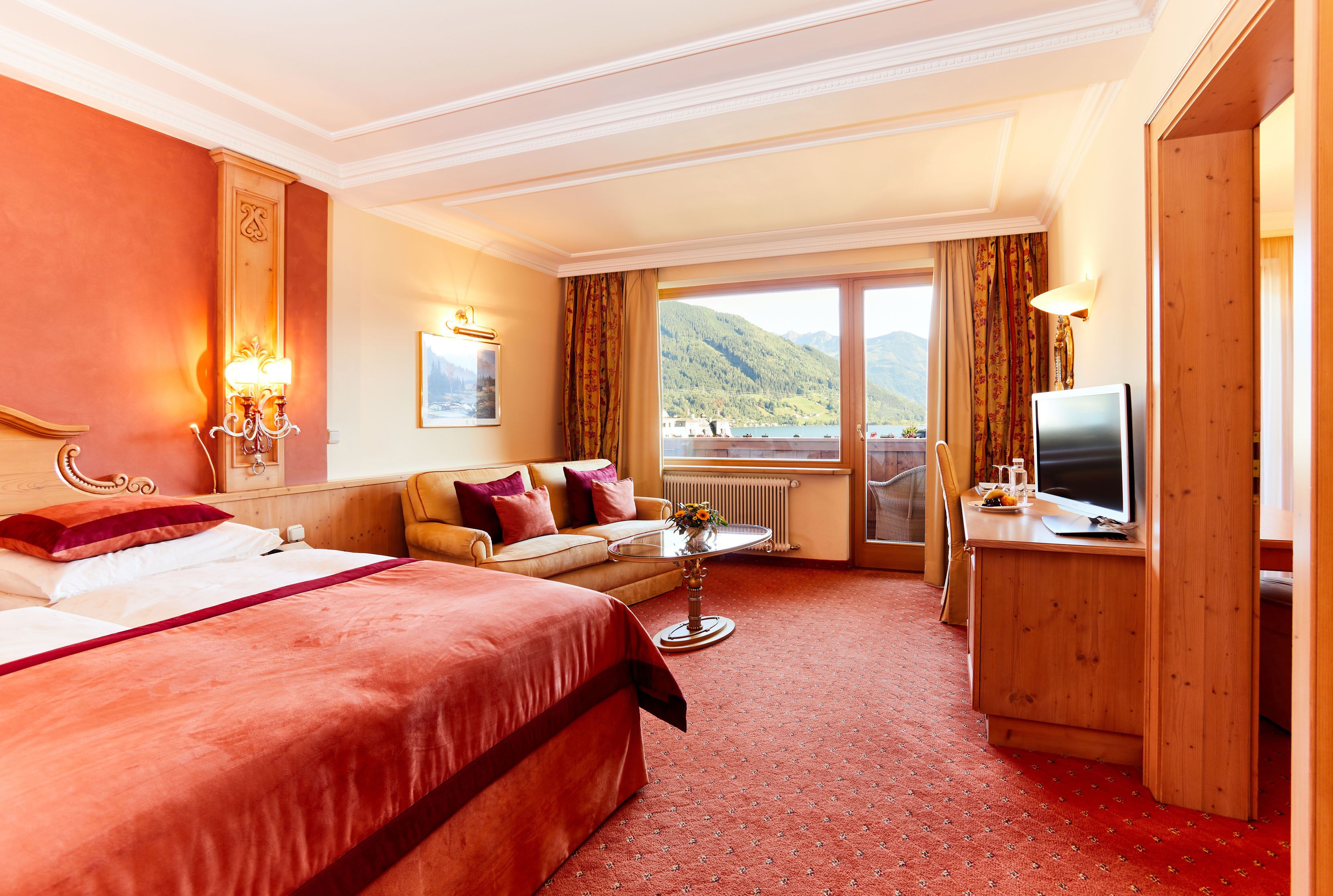 Habitación de hotel con una cama grande, un sofá, una televisión y vistas a la montaña.