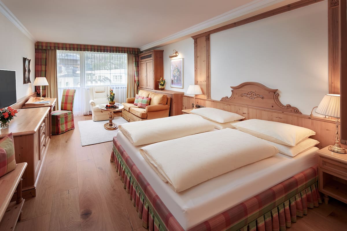 Een hotelkamer met een groot bed, een bureau met stoel, een bank en een televisie.