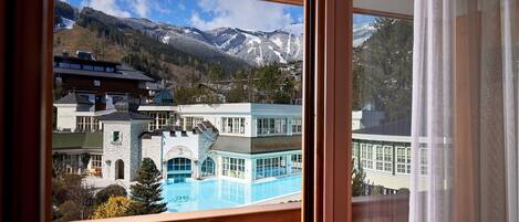 Vista desde un balcón sobre un paisaje montañoso con piscina y edificios.