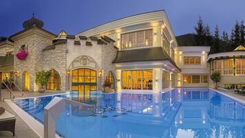 A luxurious pool area with a stone building, a gazebo, and lounge chairs.