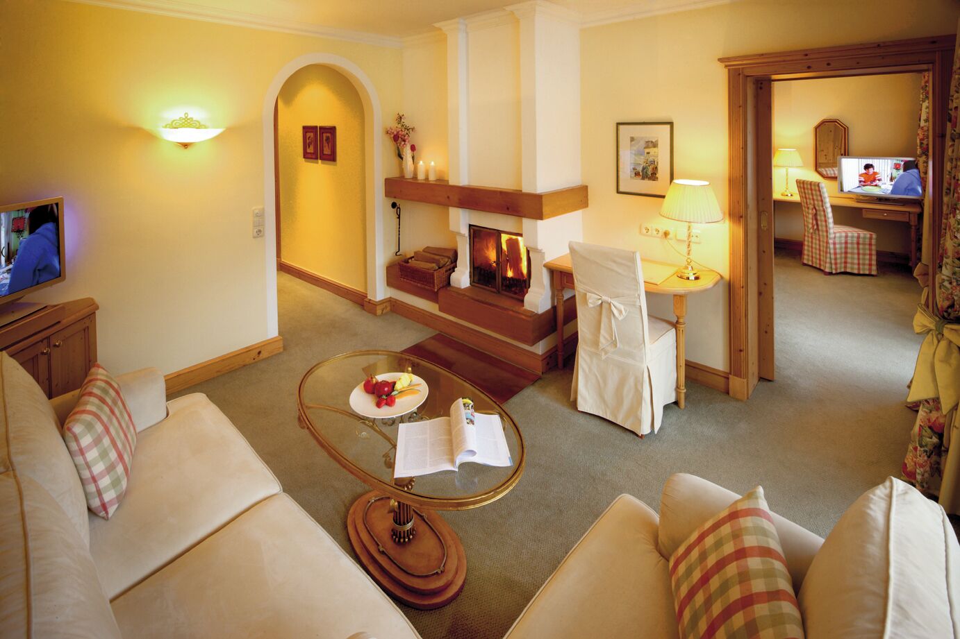 Ein gemütliches Wohnzimmer mit Kamin, Fernseher und Essbereich mit Tisch und Stühlen.