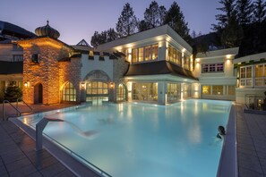 A swimming pool area with a stone building and a modern house with large windows and a balcony. - Hotel Salzburgerhof (Zell am See)