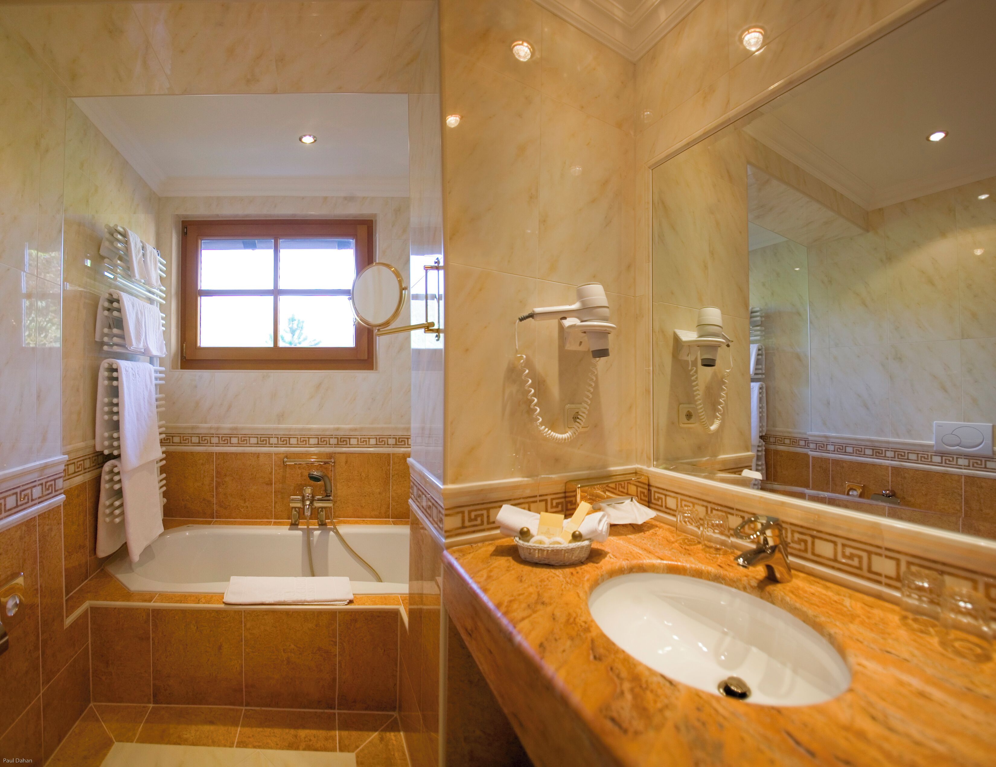 Un baño con bañera, lavamanos y un espejo grande.