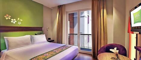 A hotel room with a bed, a small table with a vase, a chair, a balcony with curtains, and a wall with a floral design.