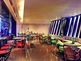 Un restaurante moderno con una zona de bar, varias mesas y sillas.