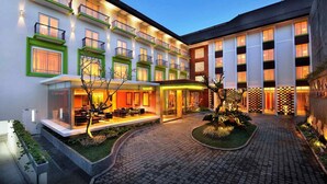 Un hotel con varios pisos, zonas de estar al aire libre y un patio con plantas.