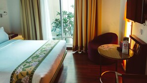 Habitación de hotel con cama, una silla, una mesita, televisor y ventana con cortinas.