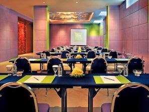 A conference room with multiple tables, chairs, and a presentation screen.