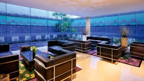 Un espacio exterior moderno con sofás de cuero y mesas, un techo decorativo y una pared con motivos florales.