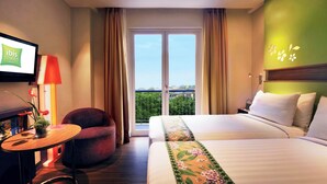 Una habitación de hotel con cama, una silla, una mesita, televisión y balcón con vistas.