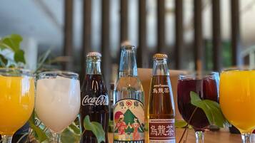 Une sélection de boissons comprenant du Coca-Cola, une bouteille de saké japonais et une bouteille de vin de prune japonais, le tout servi dans des verres transparents.