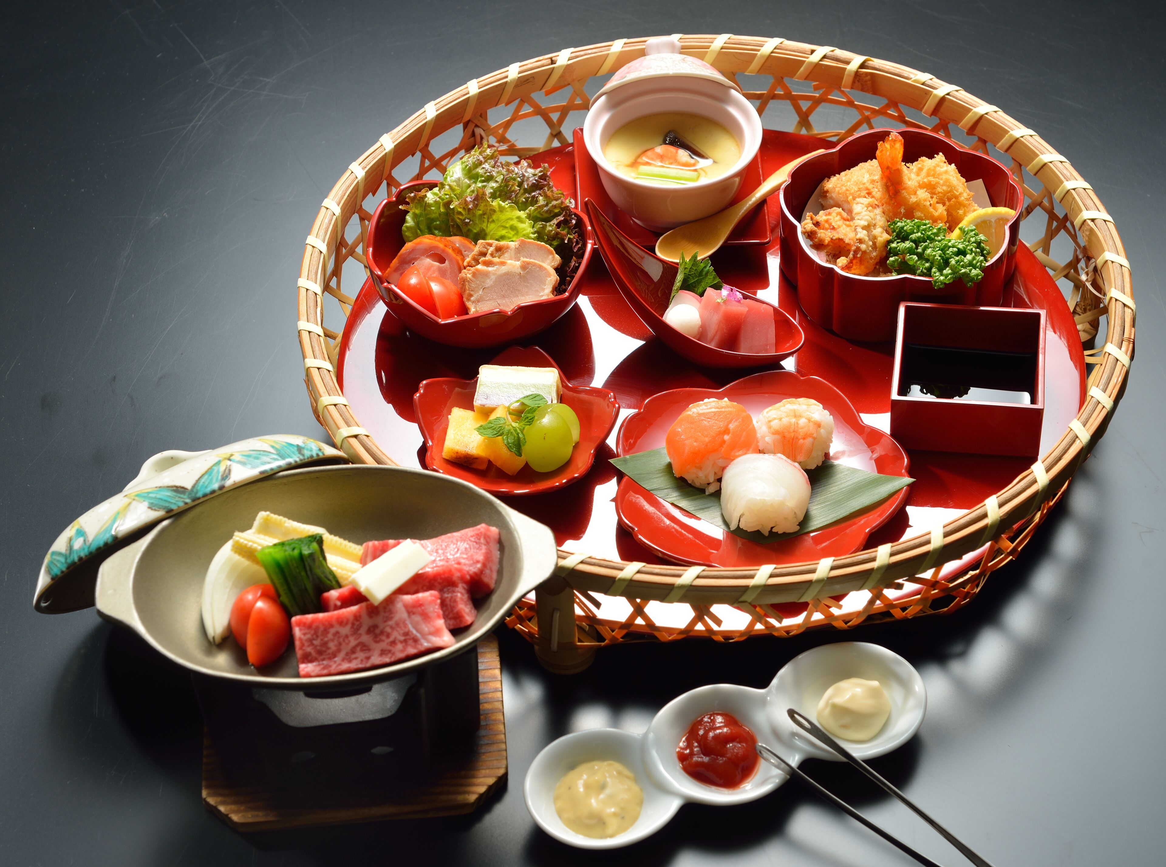 A traditional Japanese bento box with various food items including sushi, sashimi, and pickled vegetables.