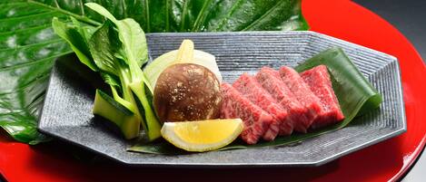 A plate of food with meat, vegetables, and a lemon slice.