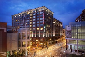 A multi-story hotel with a prominent corner location, large windows, and a well-lit facade. - Embassy Suites by Hilton St. Louis Downtown (St. Louis)