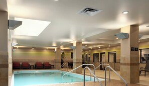 An indoor swimming pool with a skylight, lounge chairs, and a tiled floor. - Embassy Suites by Hilton St. Louis Downtown (St. Louis)