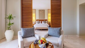 A modern hotel room with a large bed, two white sofas, a coffee table with fruit, and a potted plant. - Sifawy Boutique Hotel (As Sifah)