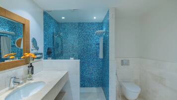 Un baño con un lavamanos grande, espejo y zona de ducha con mosaicos azules.