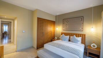 A bedroom with a large bed, wooden wardrobe, bedside lamps, and a wall-mounted artwork.