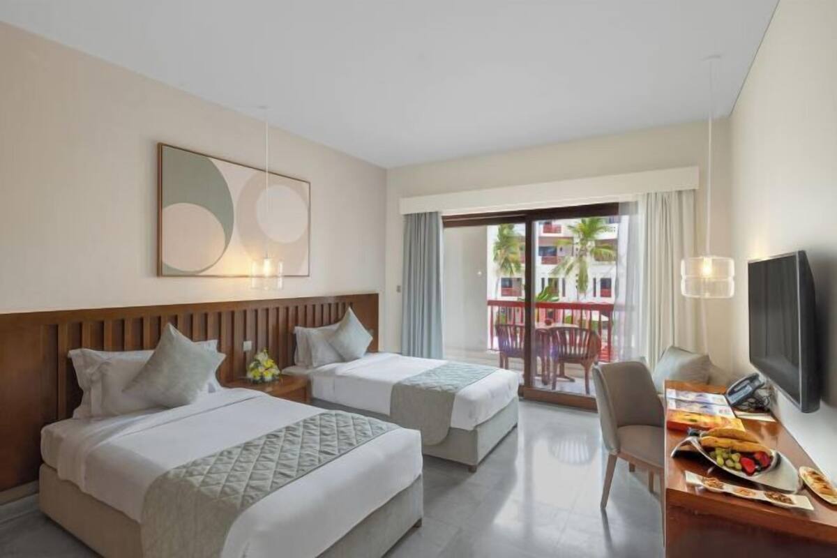 Une chambre d’hôtel avec deux lits, un bureau avec un petit-déjeuner inclus, une télévision et un balcon avec vue.
