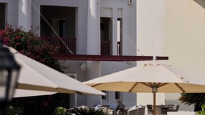 A modern building with a balcony, a staircase, and outdoor seating with umbrellas. - Sifawy Boutique Hotel (As Sifah)