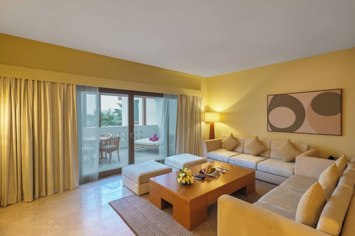 Une chambre d’hôtel équipée d’un canapé, d’une table basse et offrant une vue sur l’extérieur grâce à une porte-fenêtre coulissante.