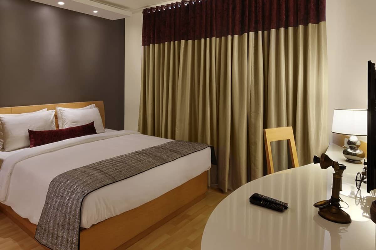 Una habitación de hotel con una cama, una mesa redonda con una lámpara y una cámara sobre la mesa.