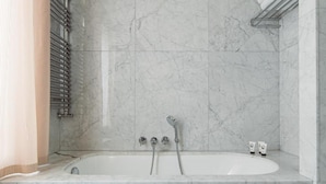 A modern bathroom with a marble floor, a bathtub, and a shower area. - Abbaye (Paris)