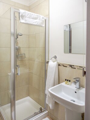 A modern bathroom with a glass-enclosed shower, a white sink, and a mirror above it. - Elmdon Lodge (Birmingham)