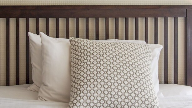 A bed with a wooden headboard and two pillows. - Elmdon Lodge (Birmingham)