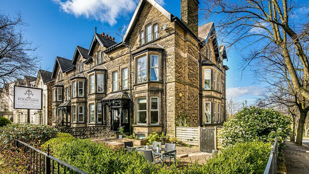 A historic stone building with large windows and a prominent corner turret. - Fountains Guest House (Harrogate)