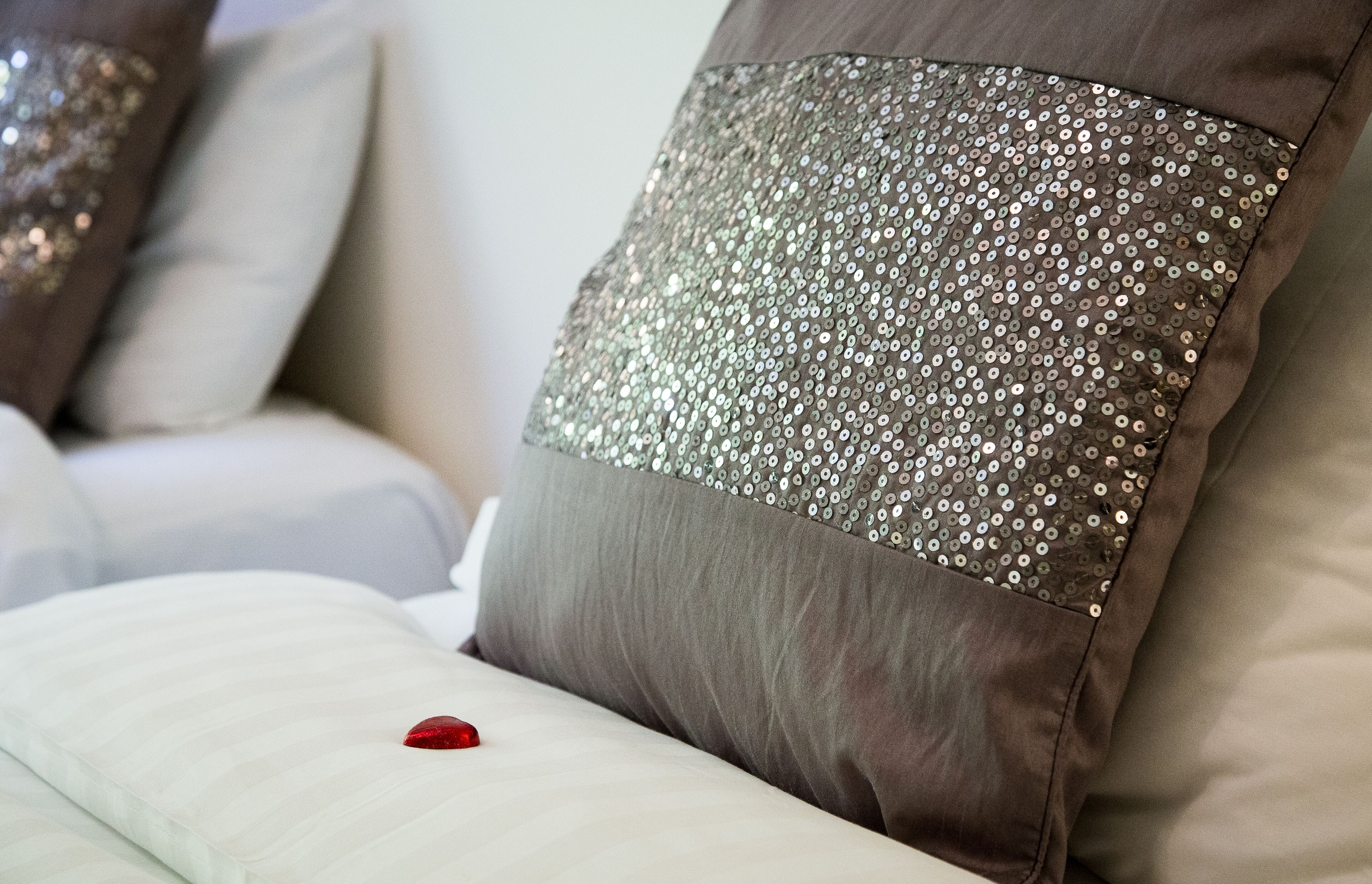 A bed with pillows, one of which has a sequined design.