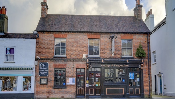 A traditional brick building with a sign for "George & Dragon Inn" and a smaller sign for "The Get Bed & Breakfast."