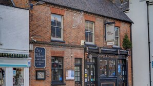 A traditional brick building with a black facade, featuring a sign for 'George & Dragon Inn' and a smaller sign for 'The G&D Bed & Breakfast' with guest rooms and a restaurant/bar.