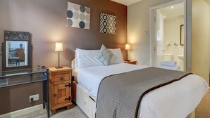 A hotel room with a large bed, two bedside lamps, a wooden nightstand, a mirror, and a wall with two decorative plates.