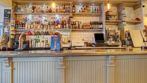 Uma área de bar com prateleiras repletas de diversas garrafas de bebidas alcoólicas, um terminal de pagamento e uma placa indicando a opção de pagamento por cartão.