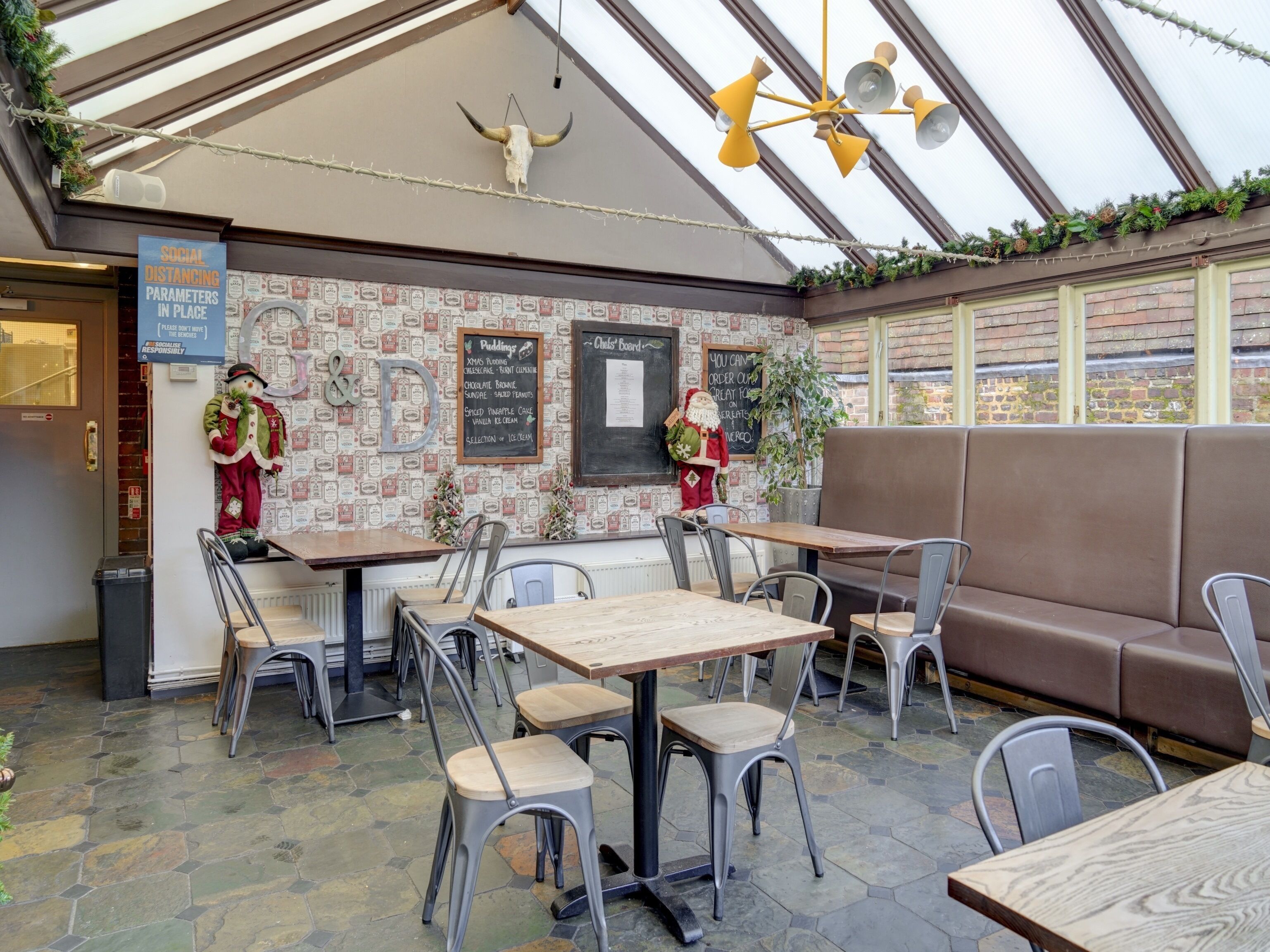 A restaurant with a brick wall, a ceiling fan, and a Christmas decoration. Tables and chairs are arranged for dining.