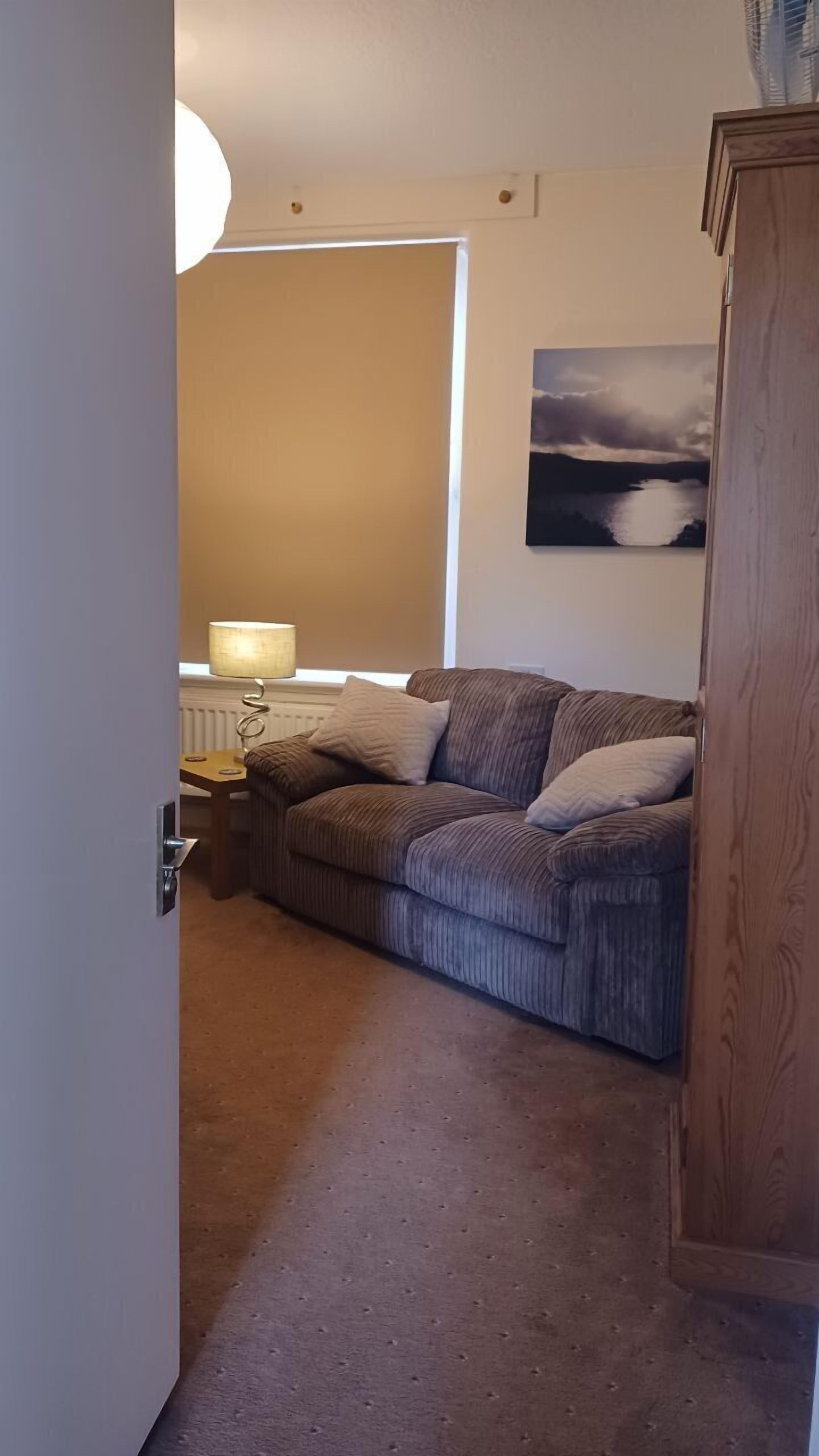 Un soggiorno con un divano, una lampada, un quadro e un mobile in legno.