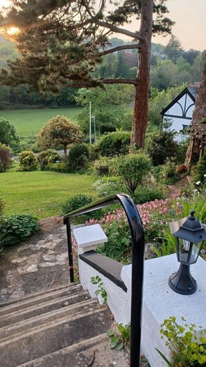 A garden pathway leading to a house with a white exterior and a black roof. - Glan Heulog Guest House (Conwy)
